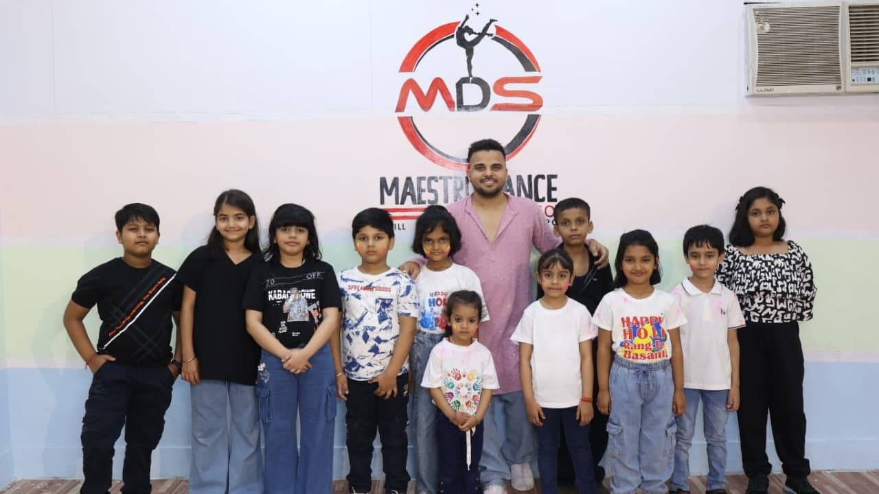 Founder with students celebrating Holi in front of the studio wall