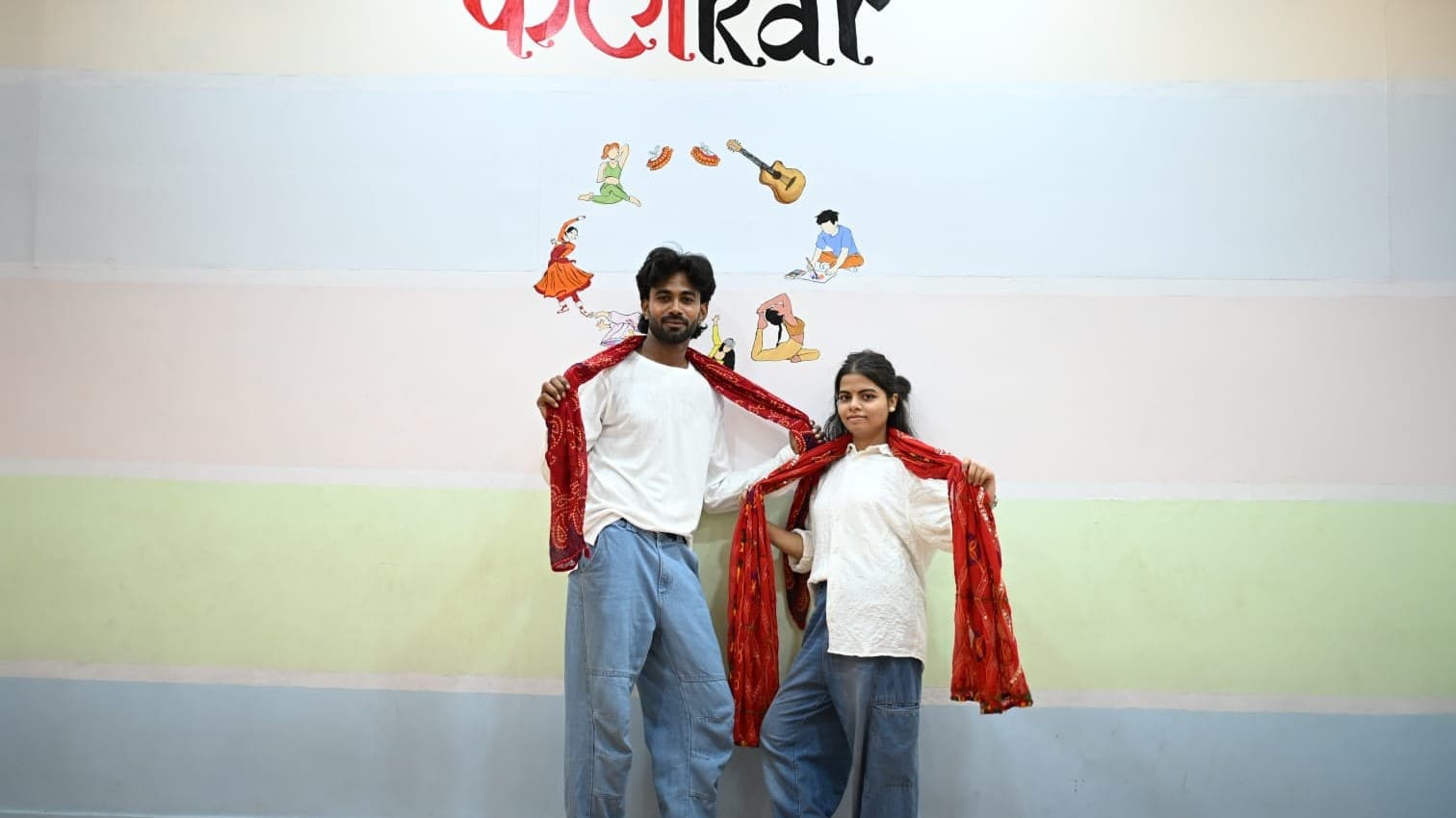 Two instructors posing together by the KalaKar mural