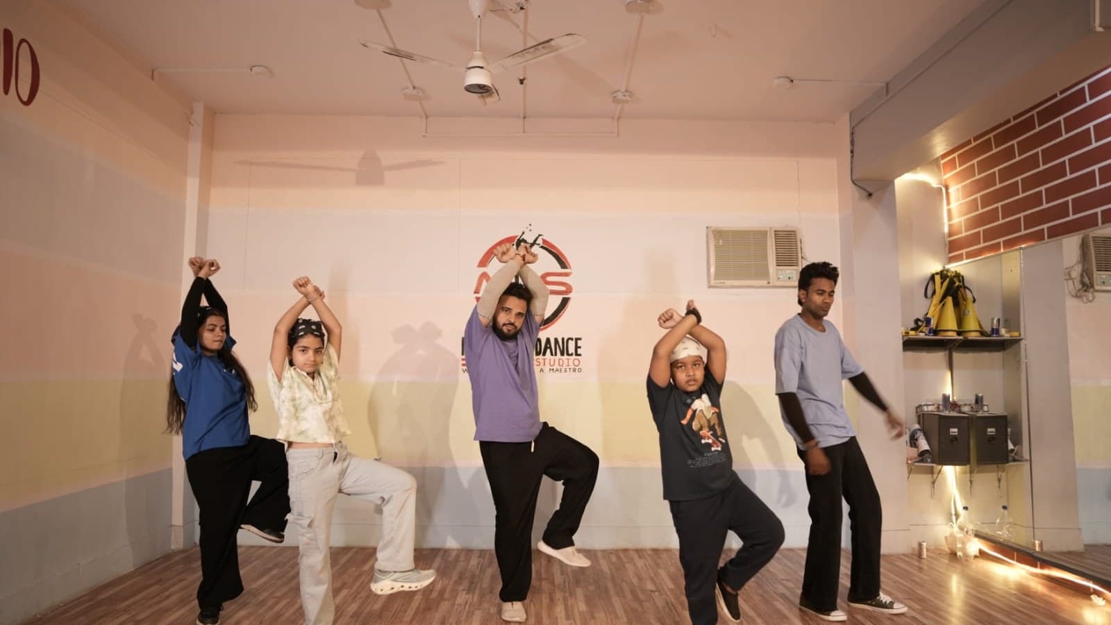 A hip-hop crew mid-pose with their instructor